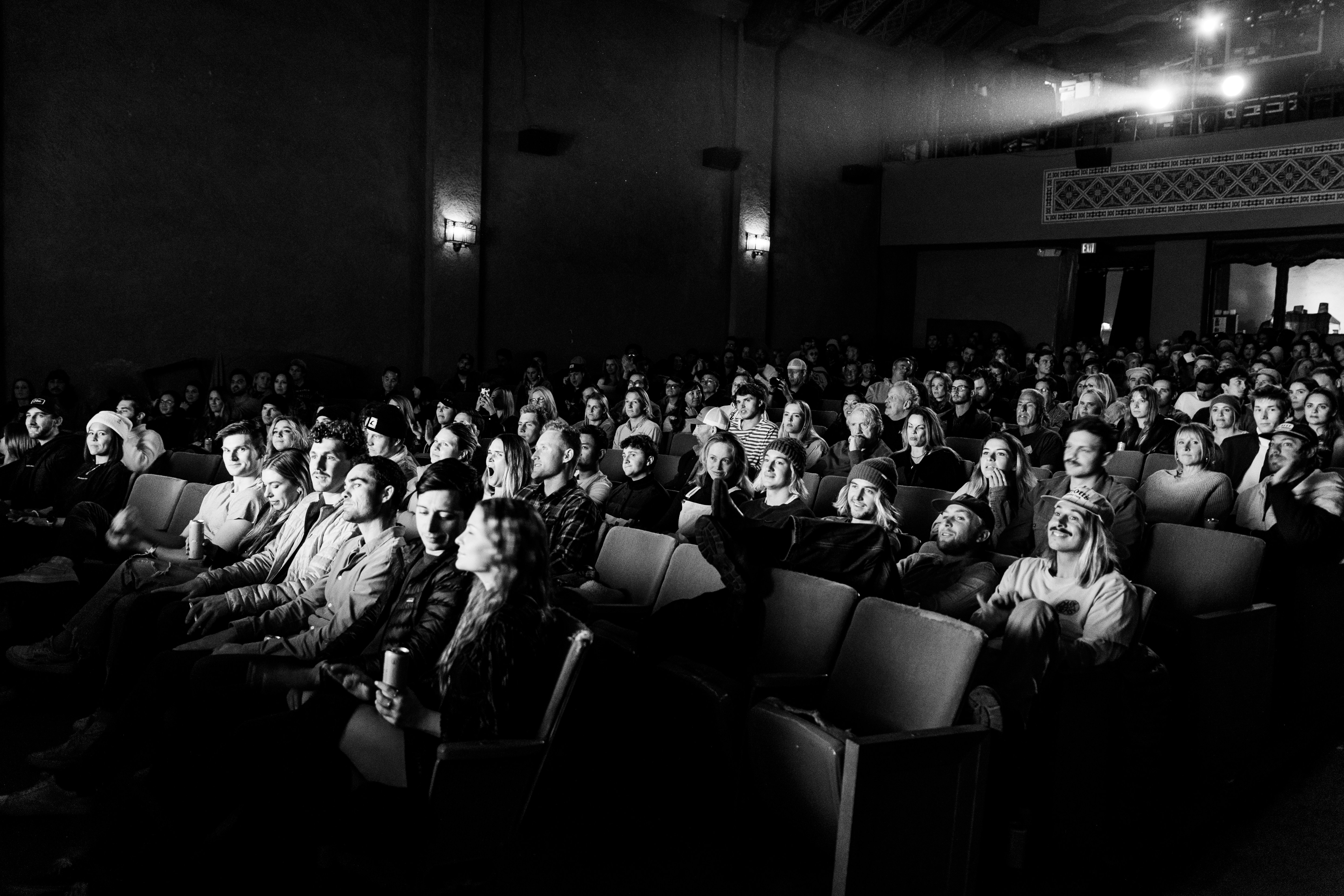 A crowded movie theater filled with an engaged audience watching a film, rendered in black and white